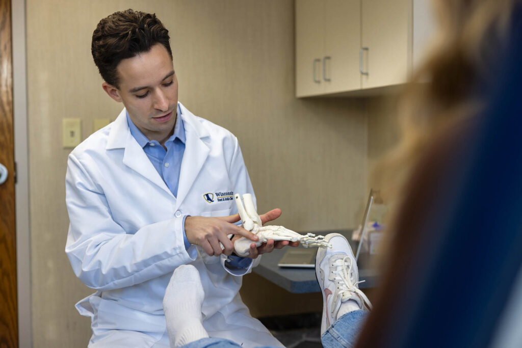 Dr. Donald T. McDonald of Wisconsin Foot & Ankle Clinic explaining foot anatomy to a patient using a medical model during a consultation.