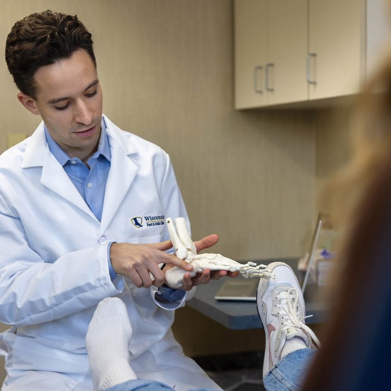 Dr. Donald T. McDonald of Wisconsin Foot & Ankle Clinic explaining foot anatomy to a patient using a medical model during a consultation.